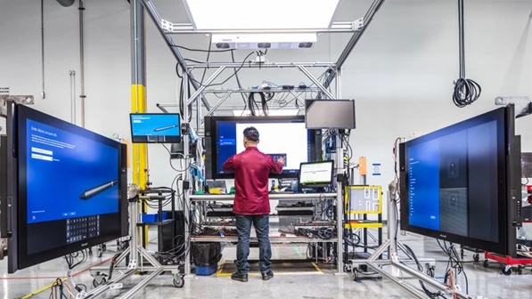 Photo of a man standing in a lab with several large touch-enabled displays