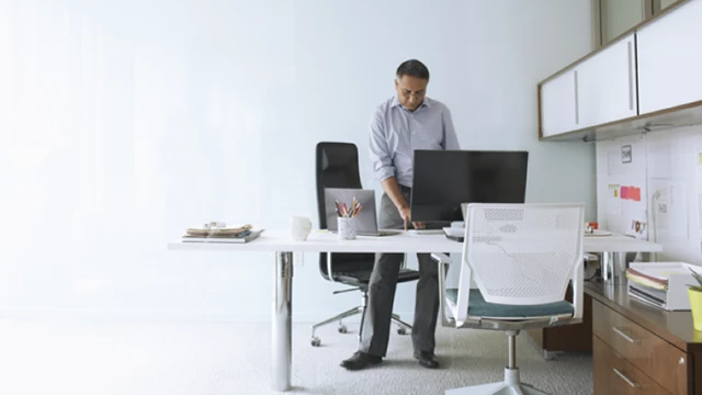 Man working at a desktop computer in a bright office.