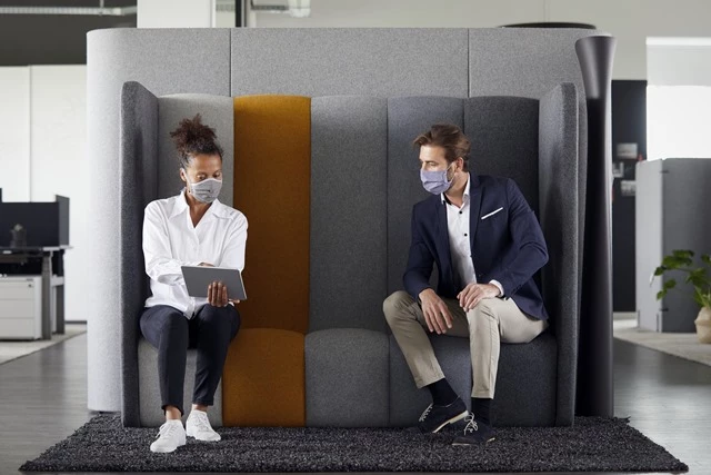 Two people wearing masks in an office setting. 