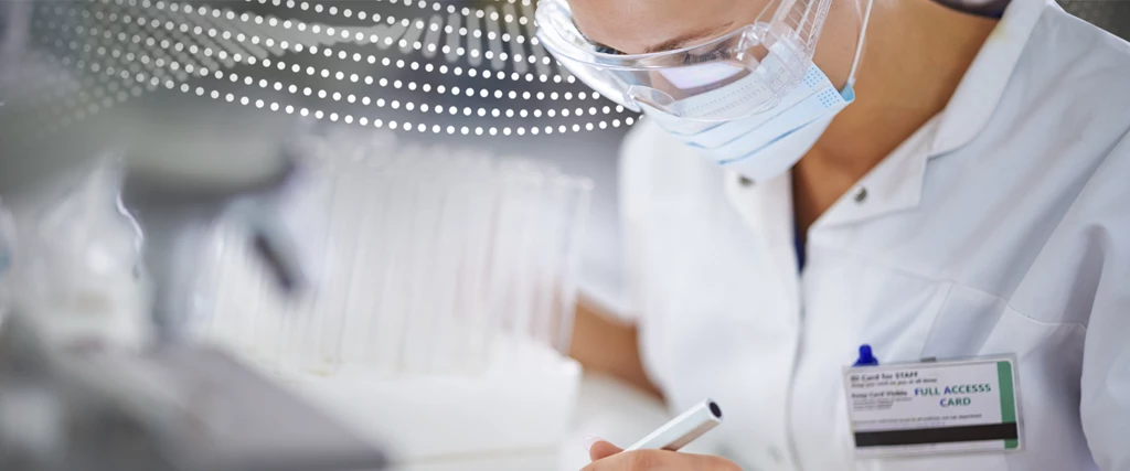 A close up of a doctor wearing a mask holding a pen.