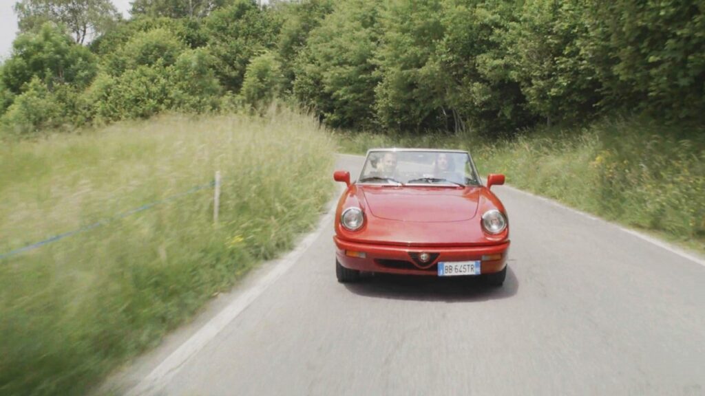 A red sports car driving in Italian countryside