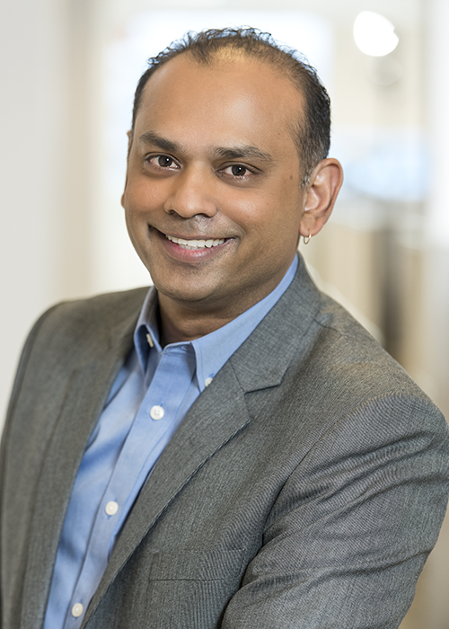 a man wearing a suit and tie smiling at the camera