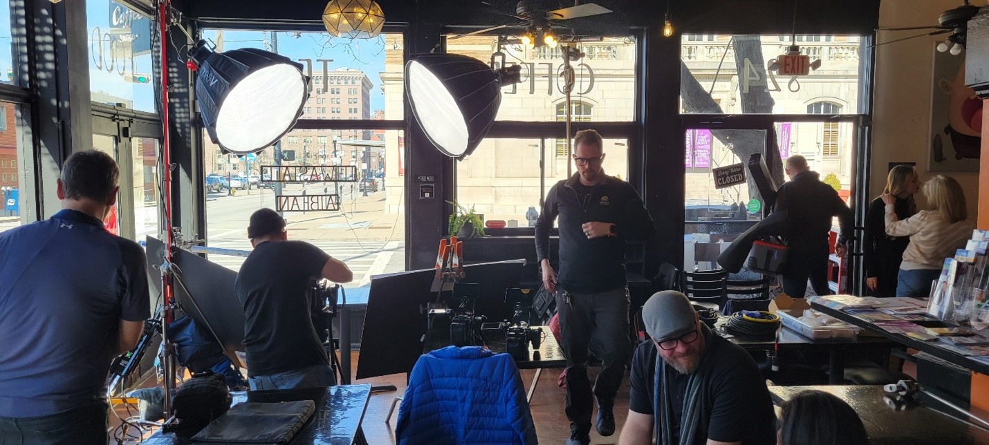 Camera crew setting up production in a coffee shop.