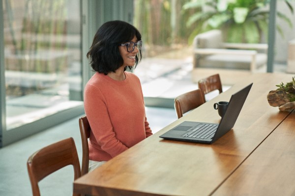 A person sitting at a table looking at a laptop.