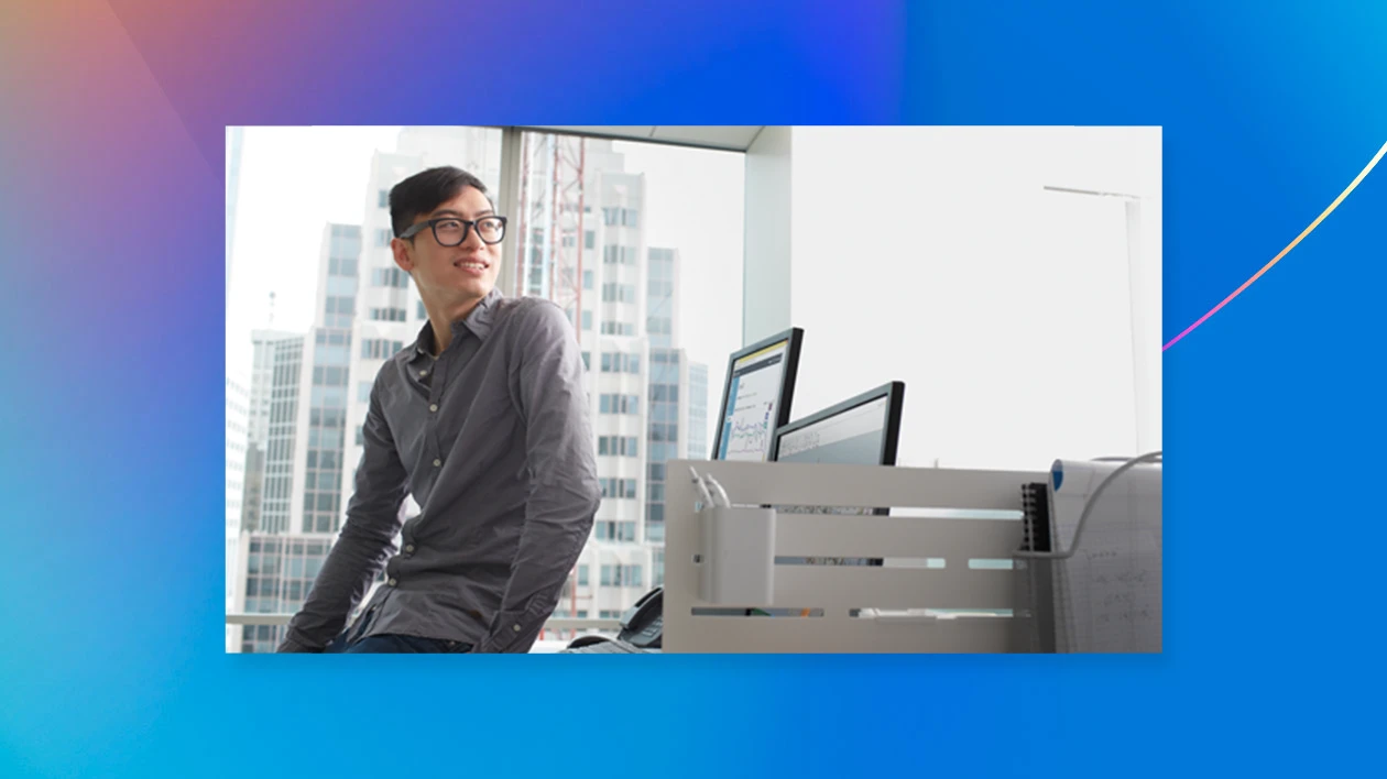 Man looking away from desktop computer with blue background
