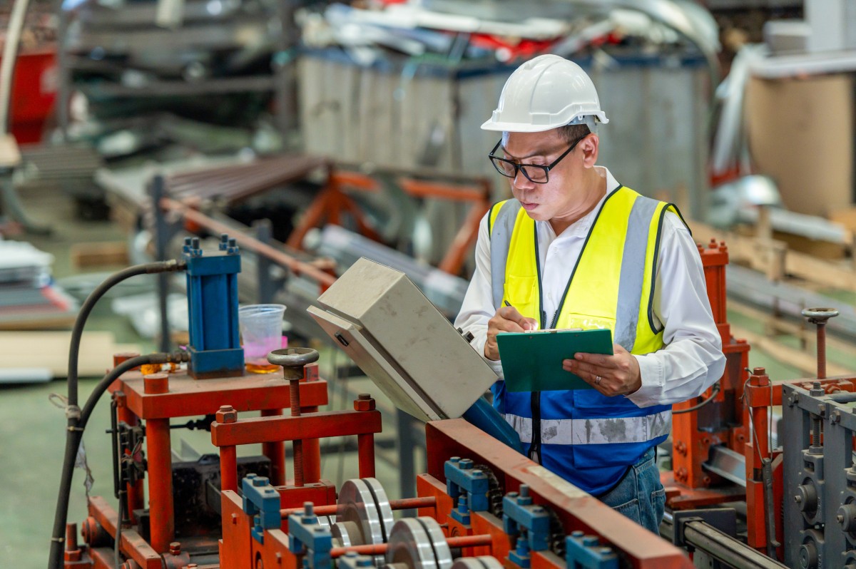 Engineer uses a digital tablet as he inspects machinery in a factory.
