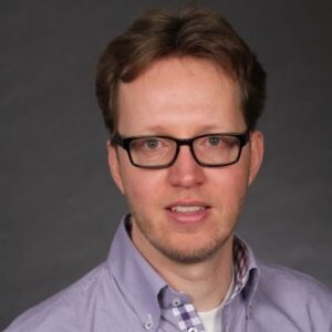 Person with glasses, light purple shirt.