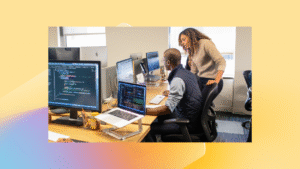 Two employees gather around a computer.