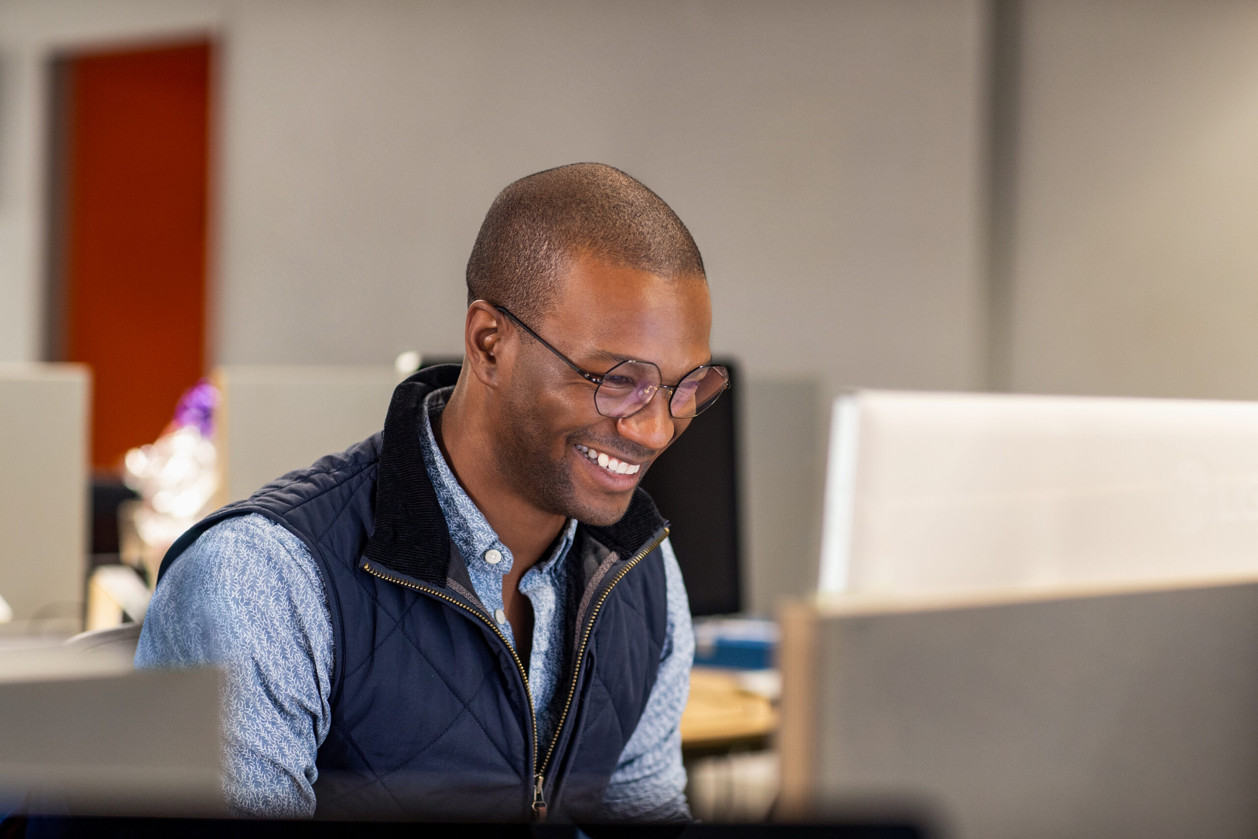 person sitting in front of the computer and smiling looking at the monitor