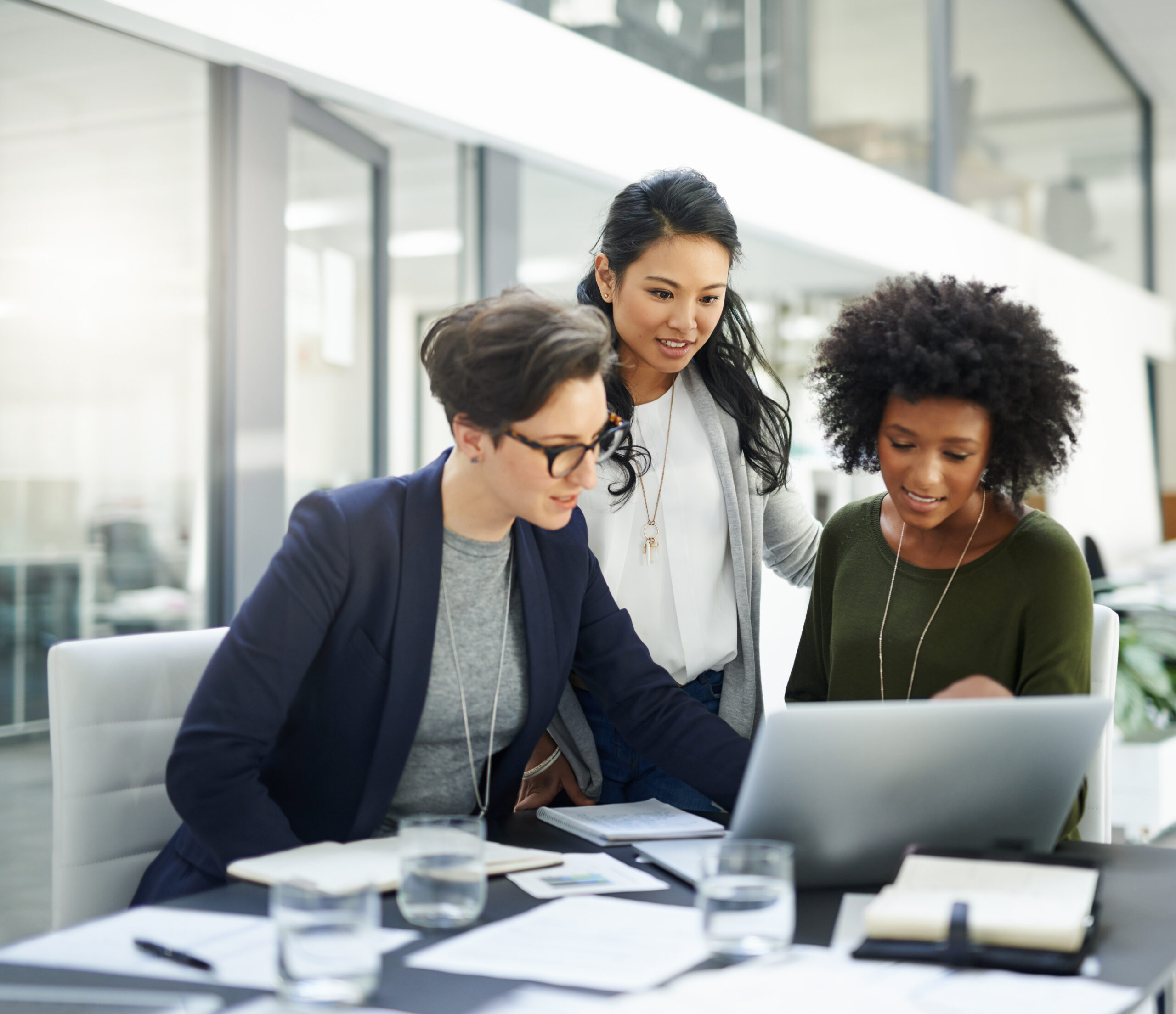 Three people looking at the laptop screen in the office environment