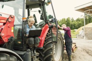Woman using laptop on tractor.