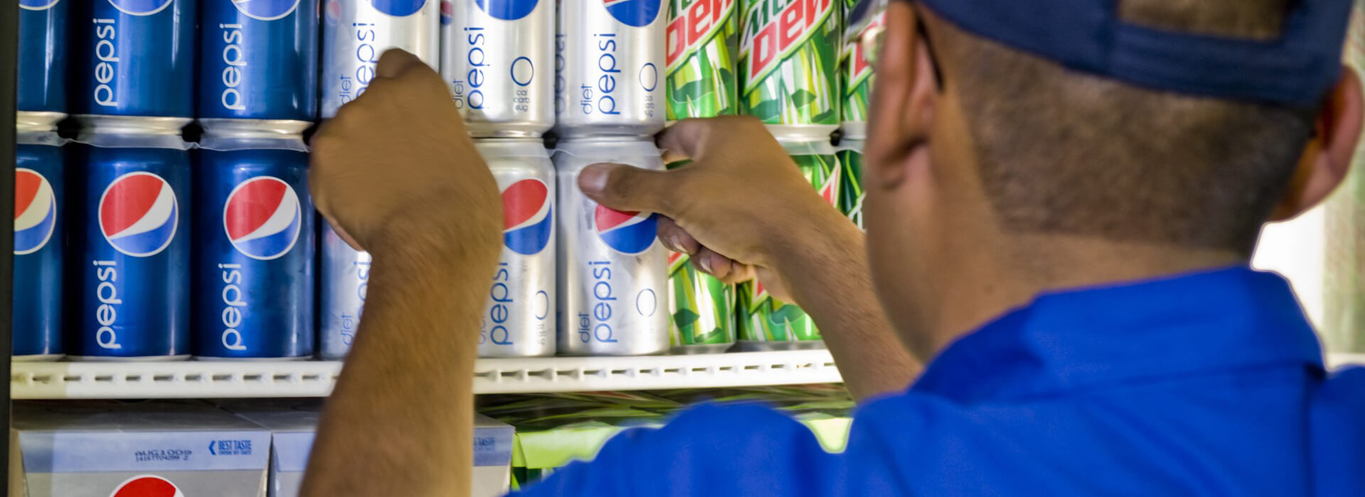 Un trabajador carga latas de Pepsi en un frigorífico.
