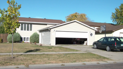 Video of a garage door opening as a car approaches it.
